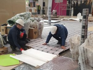 2 mans installing vinyl floor on a exhibition booth